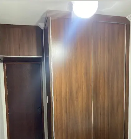 Guarda-roupa em madeira escura com maleiro montado em quarto
