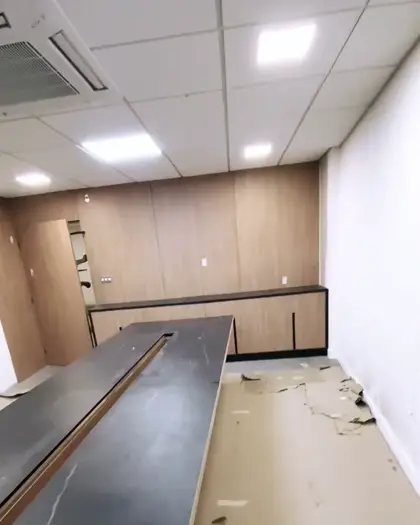 Sala comercial com painel amadeirado e bancada em pedra escura