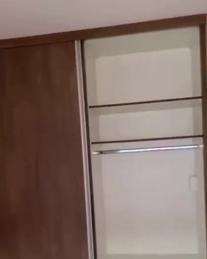 Roupeiro amadeirado com portas de abrir montado em quarto
